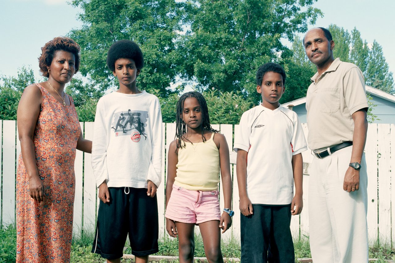 five african canadians standing in front of a fence