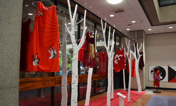Red dresses hang from white trees in an Indigenous art installation at Dal's Killam Library.