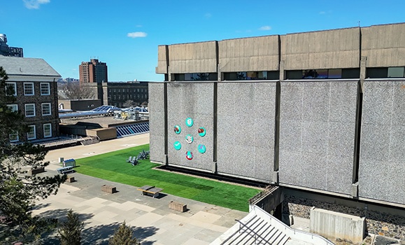 An ariel shot of the brutalist walls of the Killam Memorial Library with seven circular paintings on the left-most panel.