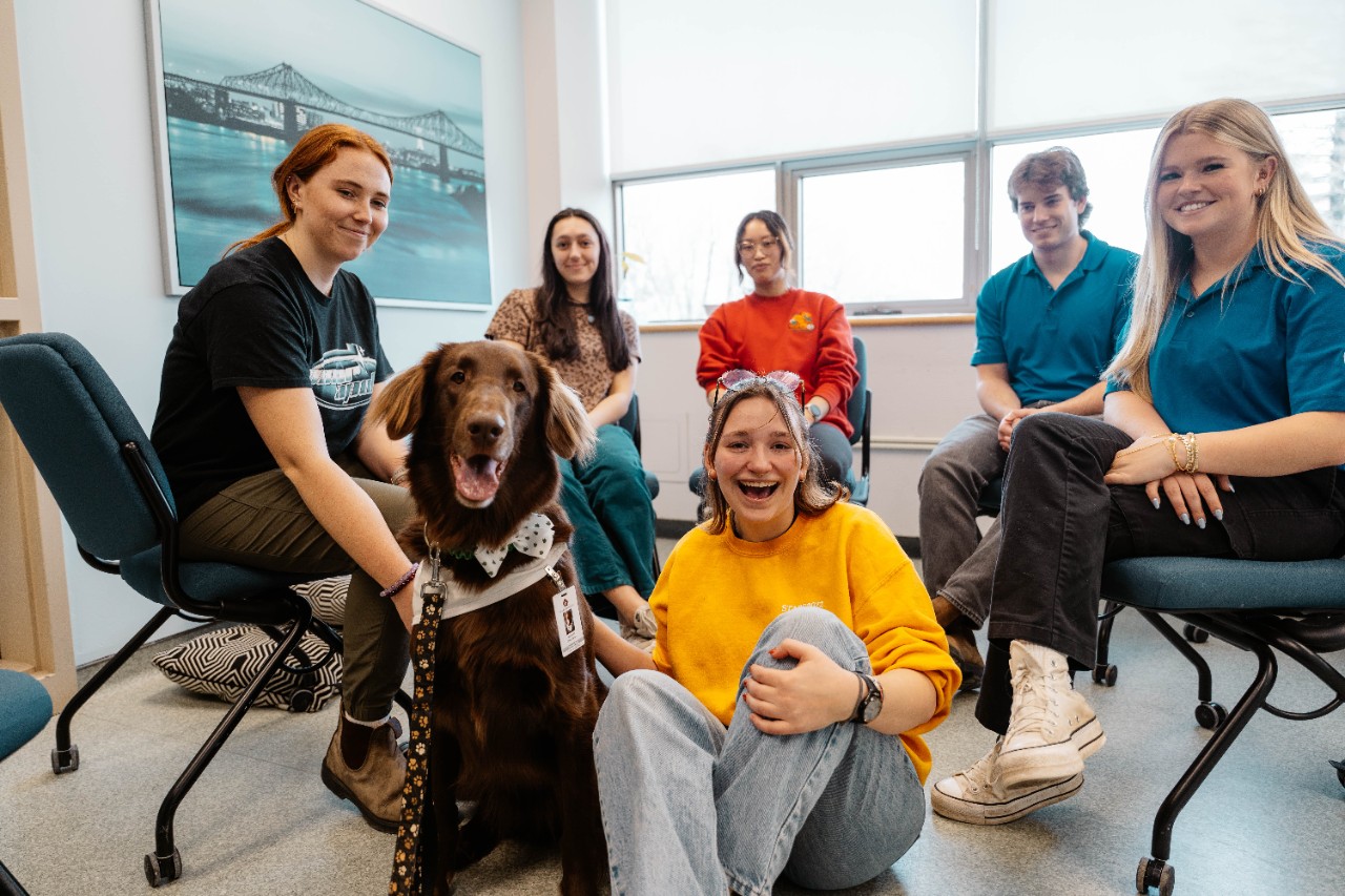 a group of students sitting in a circle with a therapy dog