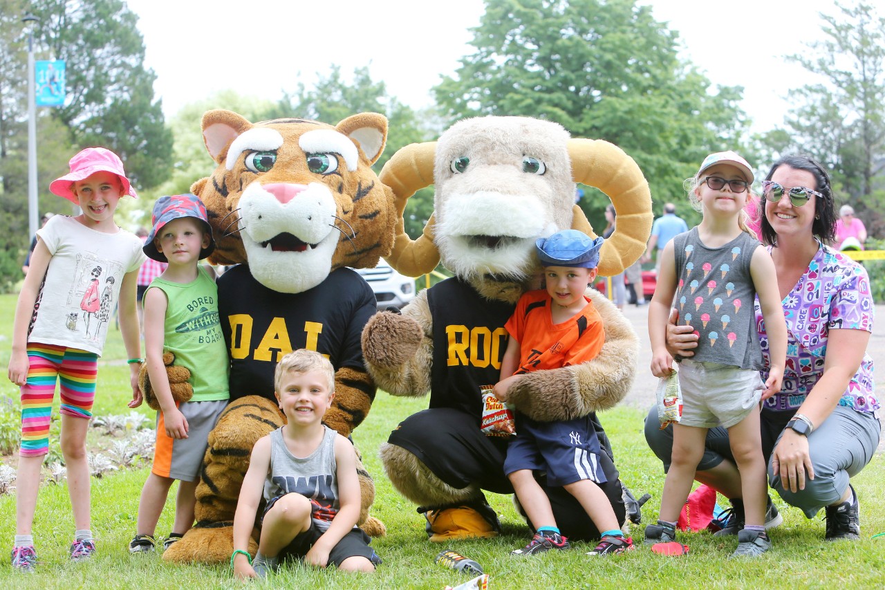 Dalhousie's tiger and ram mascots pose for a photo with a group of children.