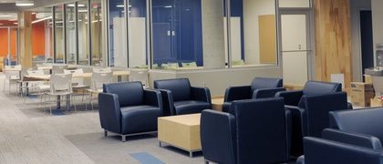 The Wallace McCain Learning Commons with a section of blue comfy chains in front and desks and white chairs behind.
