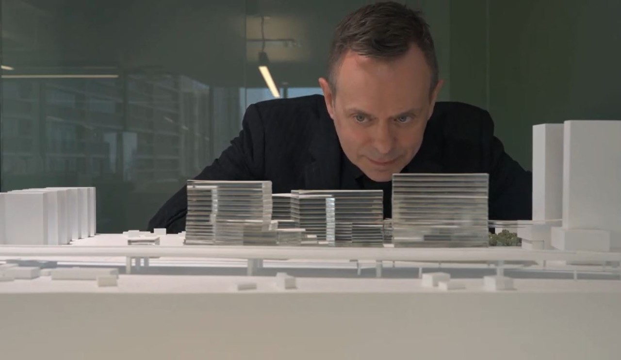 A man is looking down at a model building.