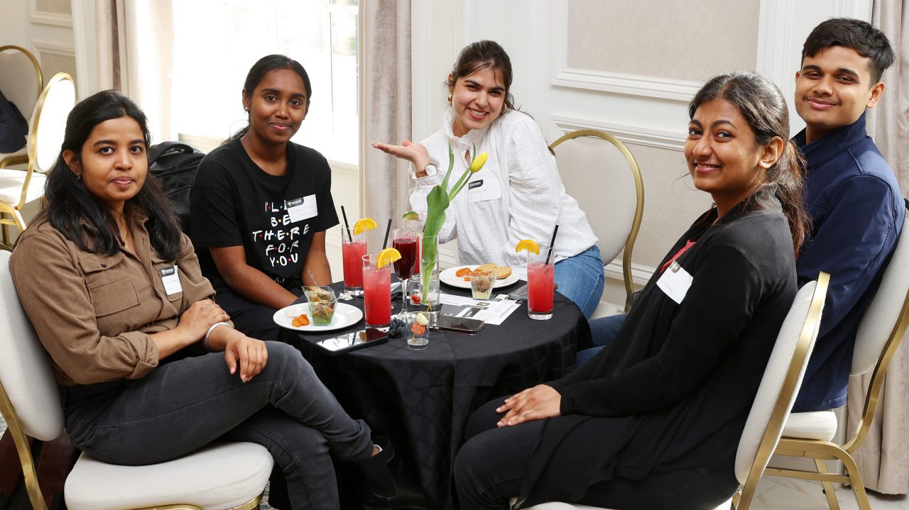 A group of people sitting around a table with food at an event.
