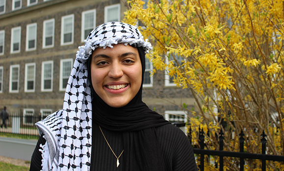 A student wearing a headscarf poses for a photo on a university campus
