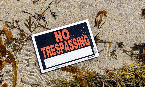 A beach displays a 'no trespassing' sign to visitors