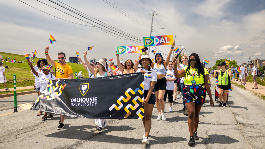 A group of people holding a black Dalhousie banner walking in a parade