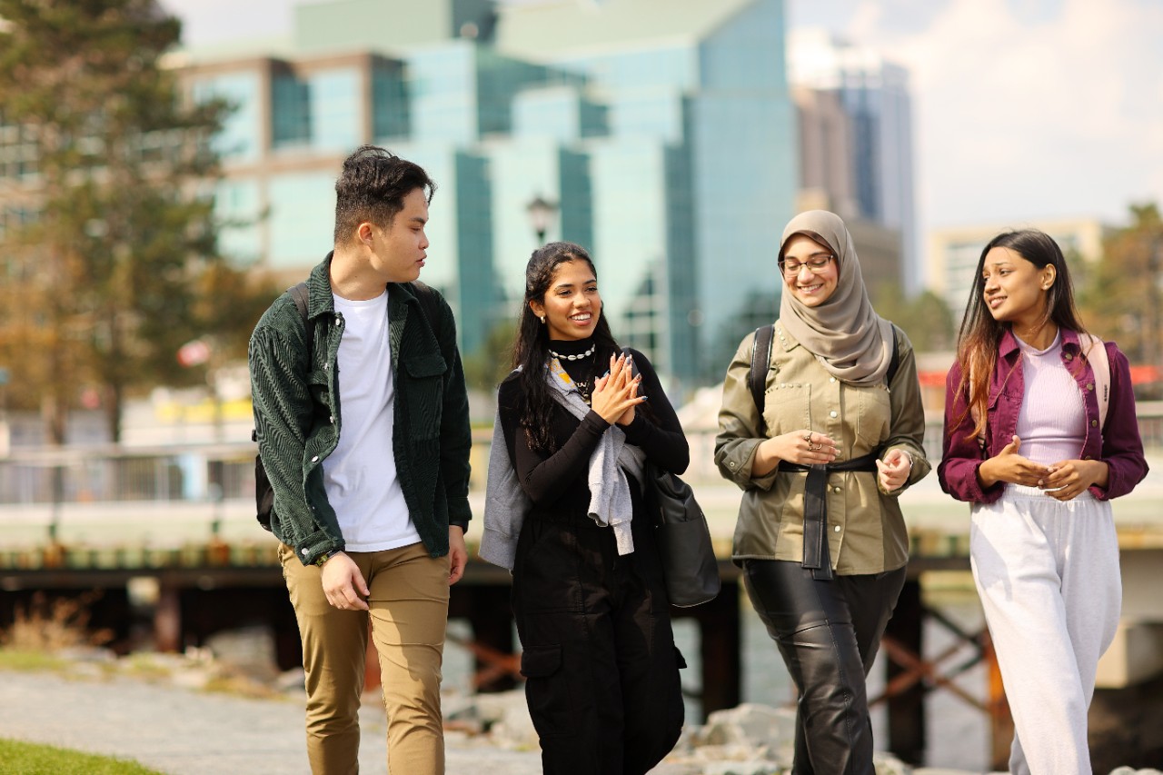 Four students walk on a path on the Halifax waterfront. 